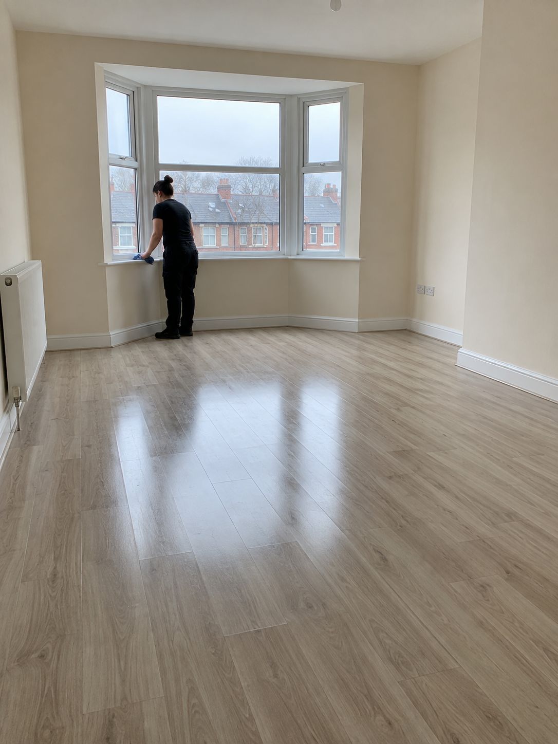 Cleaner wiping the window sill in an empty, freshly cleaned rental flat