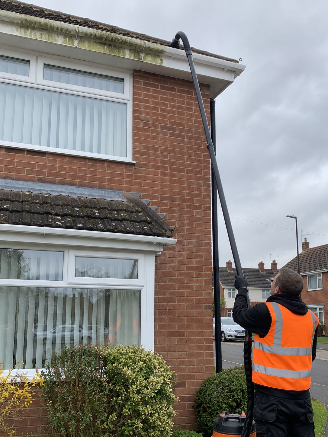 Gutter vacuum pole clearing the gutter of a semi-detached house