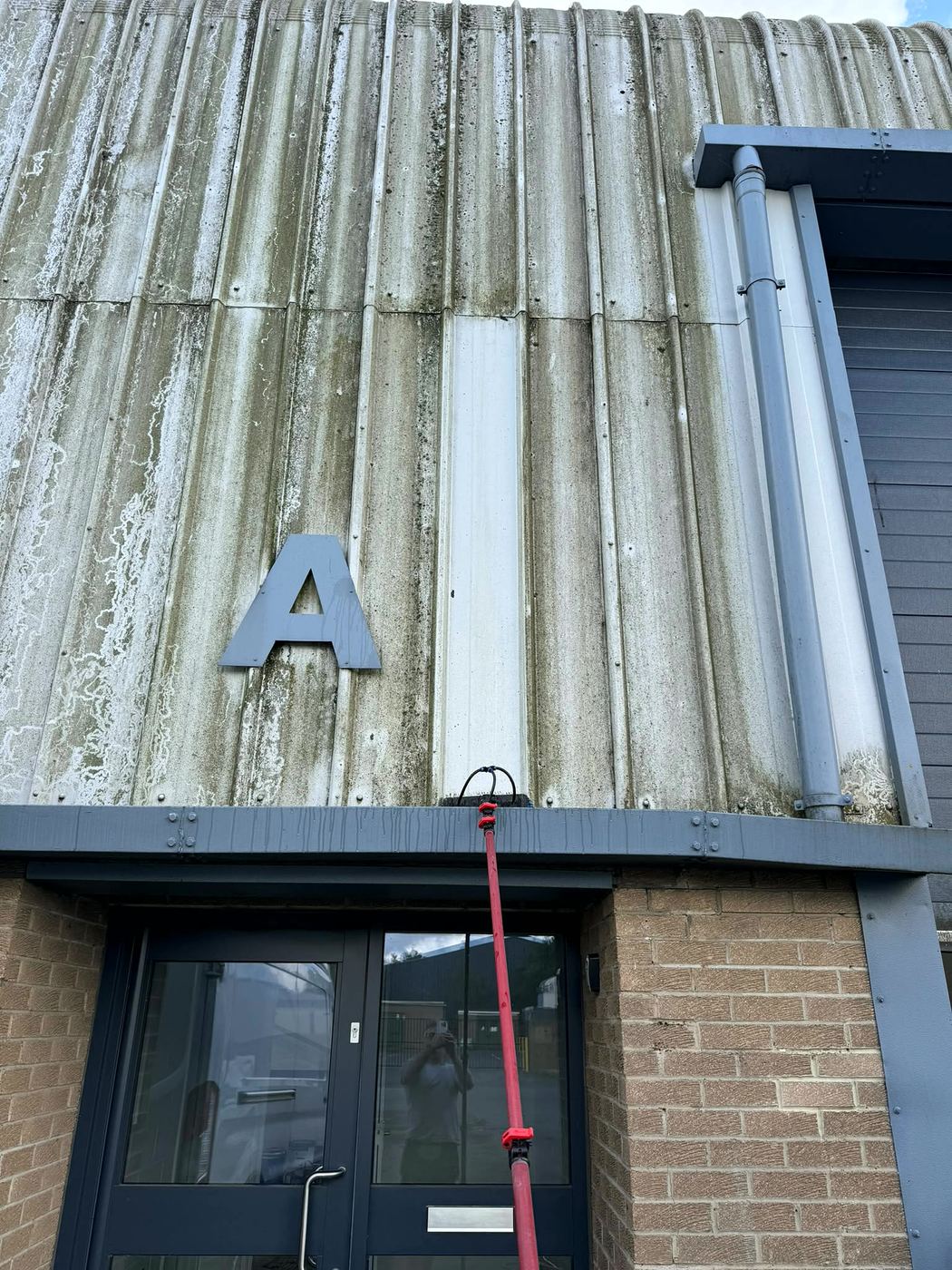 Industrial unit cladding with one cleaned strip showing the difference